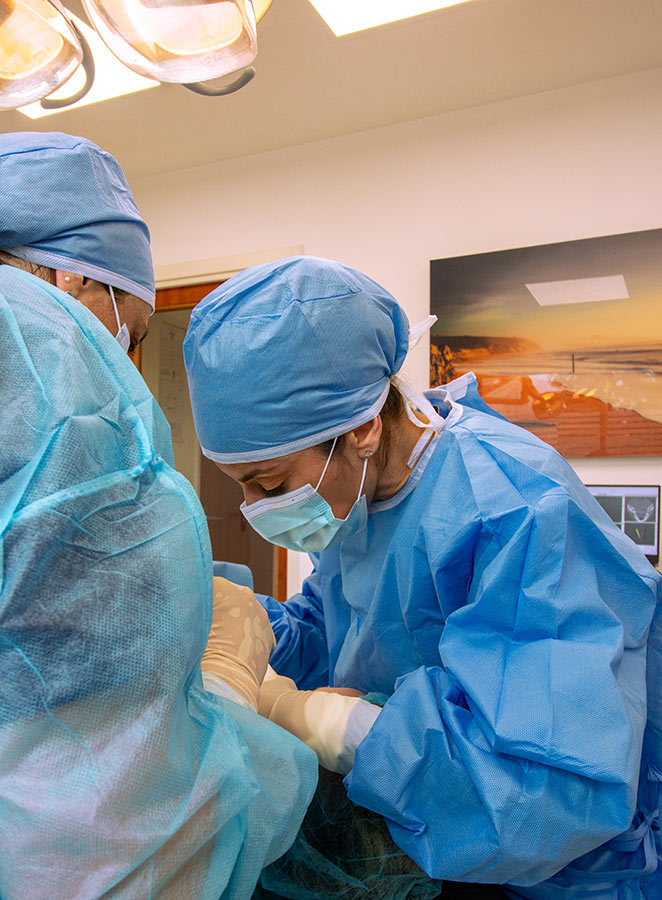 Docteur Stéphanie Henriques, chirurgien dentiste à Albi (81) spécialisée en implantologie et parodontie en tenue stérile effectuant un soin.